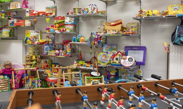 Eine Menge Spielzeug steht in einem Raum auf Wandregeln und davor.
