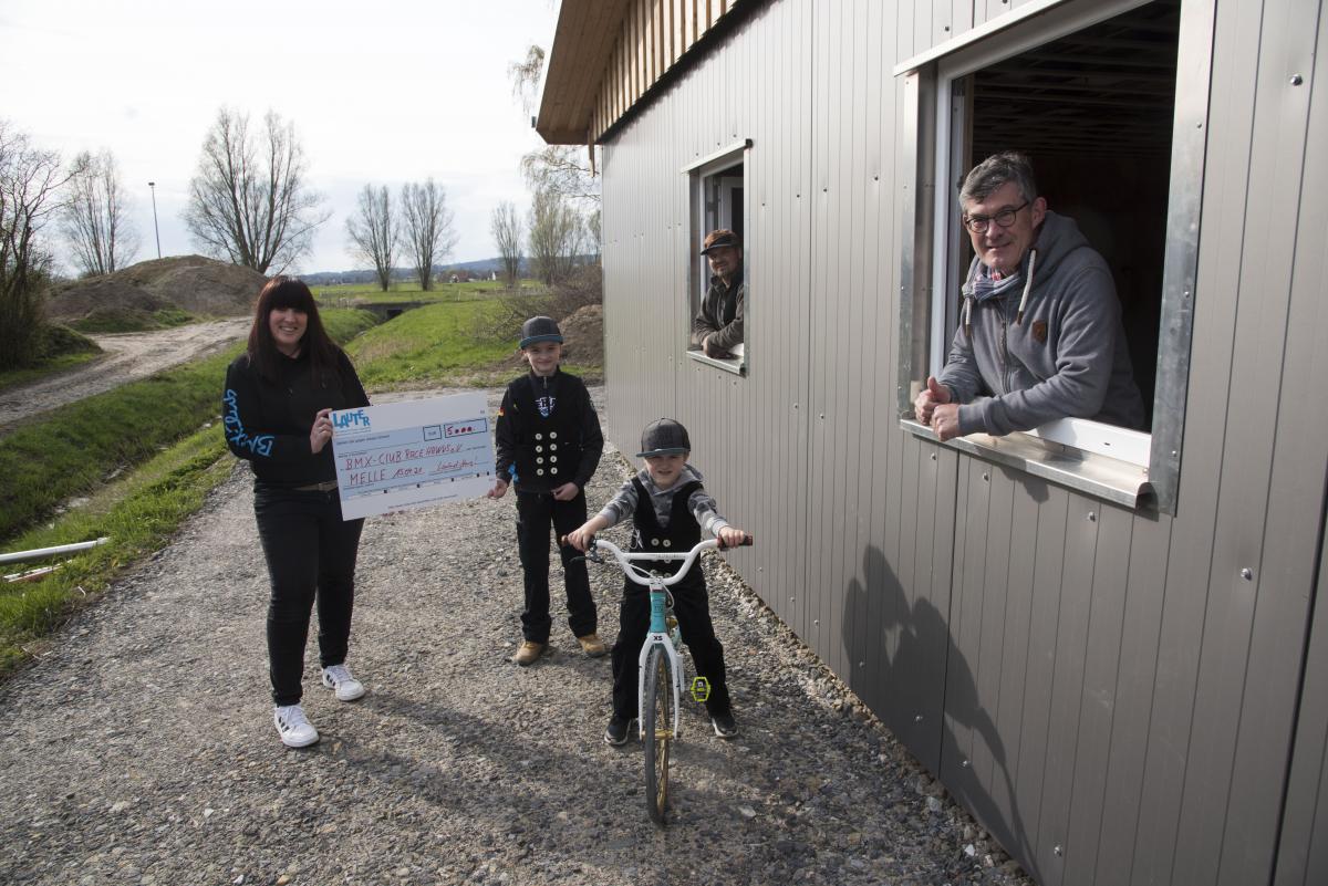 Scheckübergabe mit 3 Personen und einem Kind auf dem Fahrrad