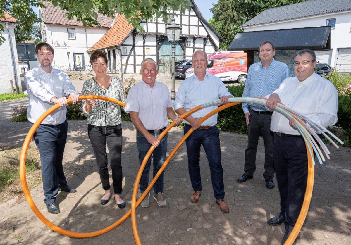 6 Personen im Freien halten ein Glasfaserkabel