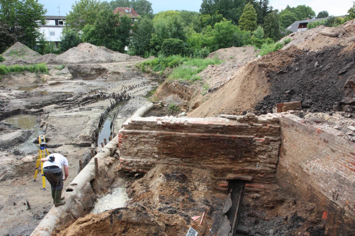 Ausgrabungen an der Kleinen Mühle in Quakenbrück Archäologische Fundstelle, die einen freigelegten Balken zeigt. Ein Mann ist an der Fundstelle tätig