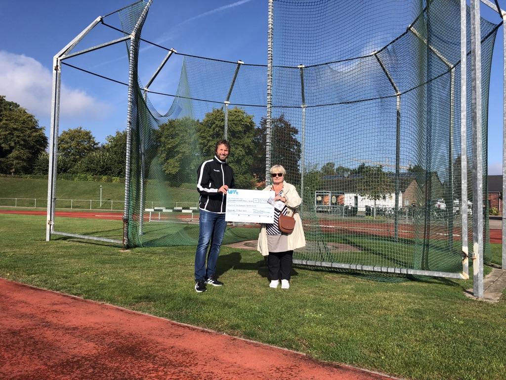 Scheckübergabe: 2 Personen auf Sportplatz