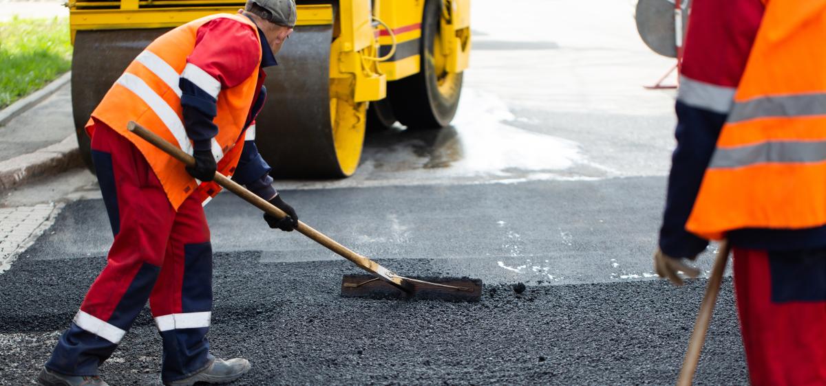 Geplante Baumaßnahmen an Kreisstraßen Straßenbauarbeiter verteilen Schotter
