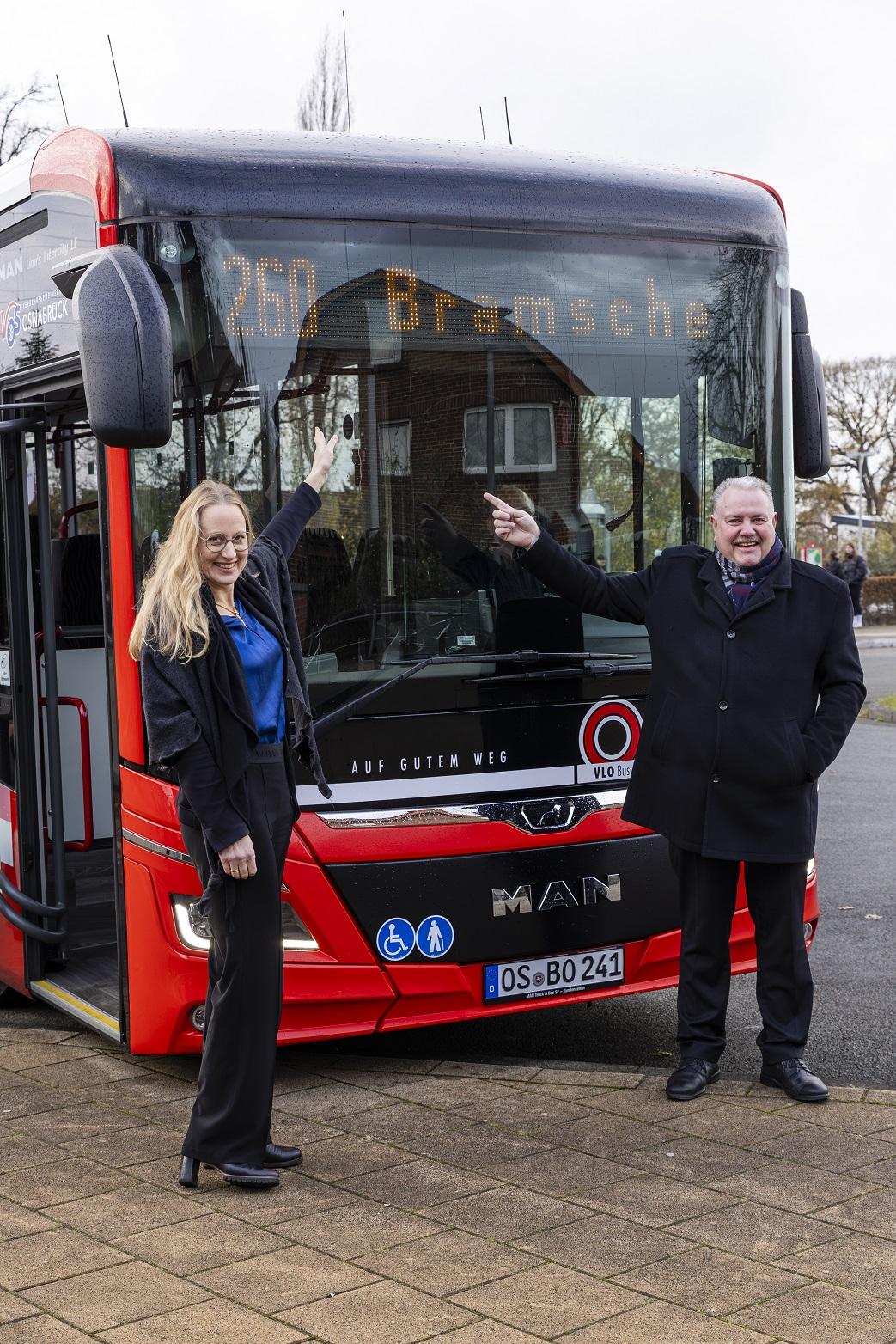Zwei Personen stehen vor einem Stadtbus.