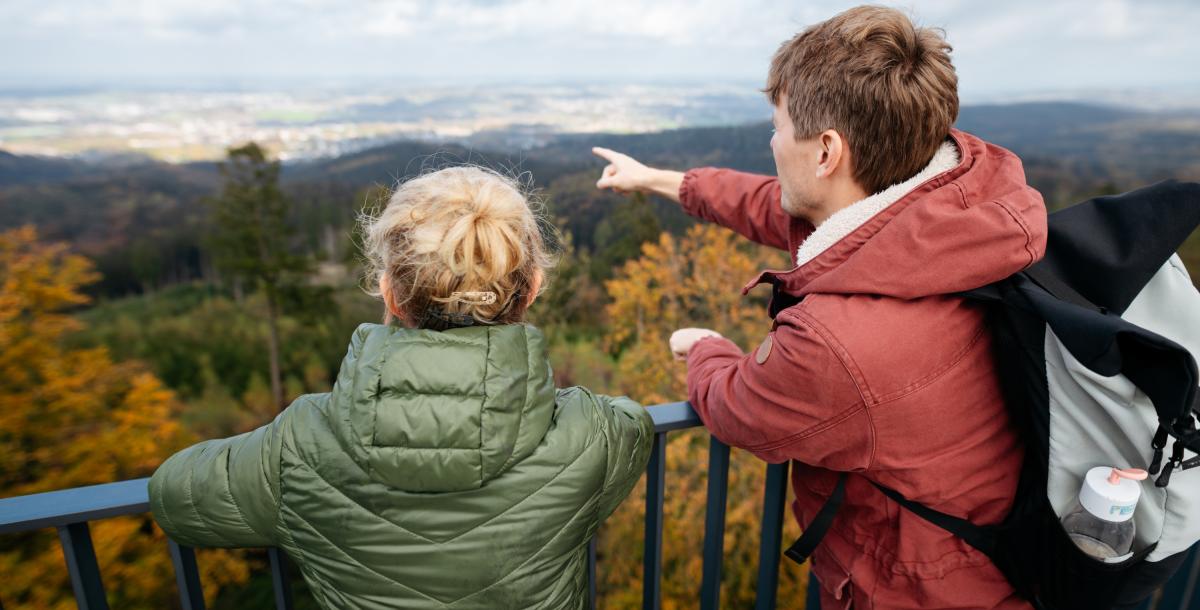 Zwei Personen auf einem Aussichtspunkt schauen in die Landschaft