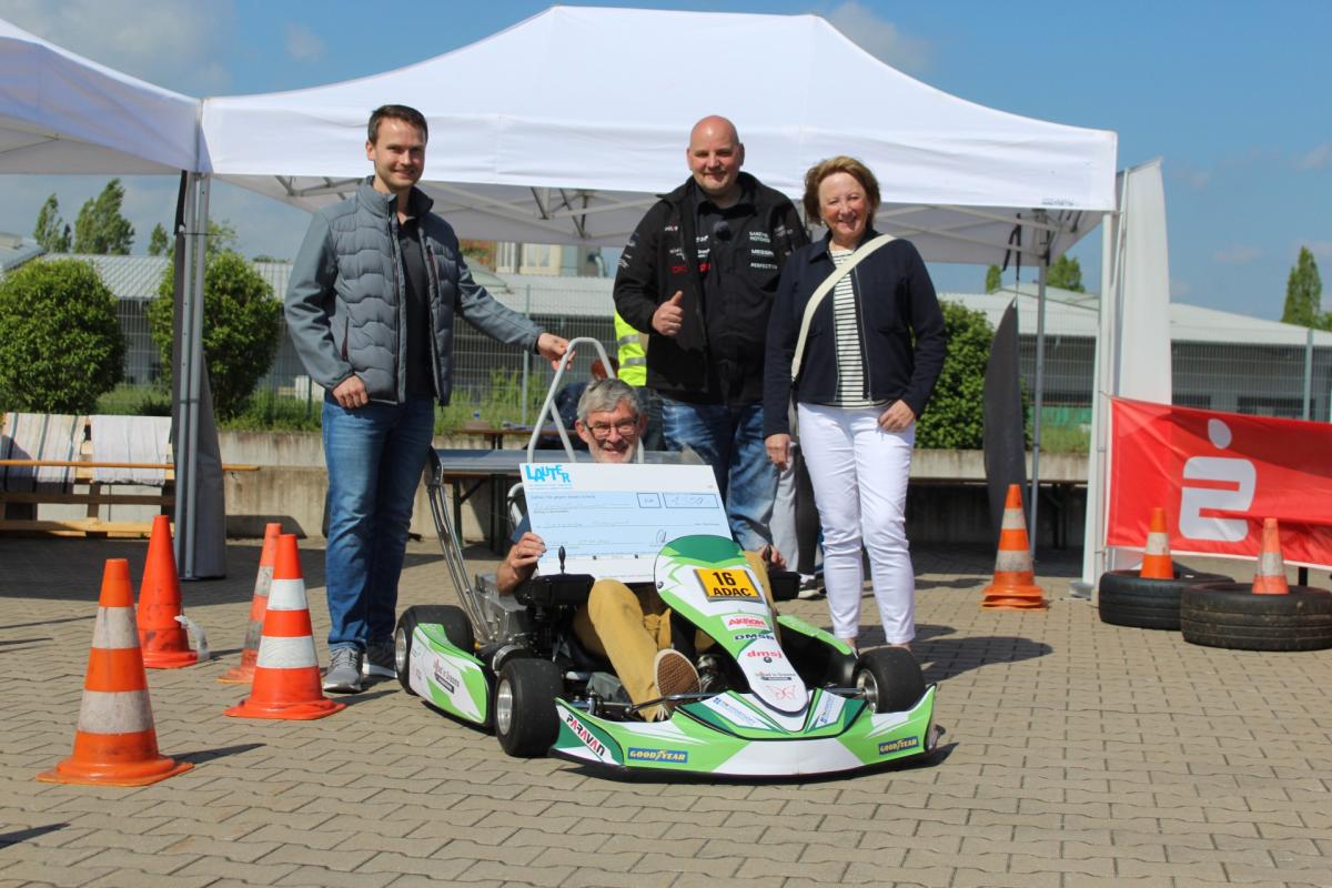 Vier Personen, eine sitzt in einem Gokart.