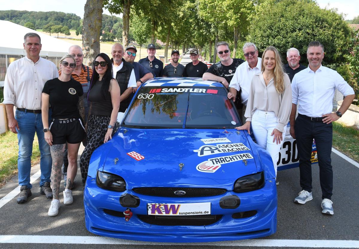 Gruppe von Personen stehend um Sportwagen