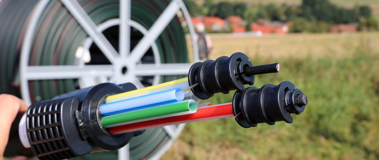 Breitband Glasfaserkabel, im Hintergrund ländliche Landschaft