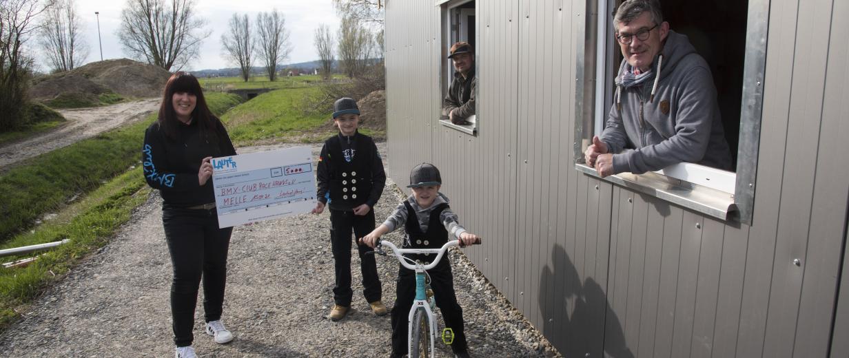 BMX-Club RaceHawks Melle: Stiftung LAUTER unterstützt Bau der neuen Wettkampfbahn mit 5.000 Euro Scheckübergabe mit 3 Personen und einem Kind auf dem Fahrrad