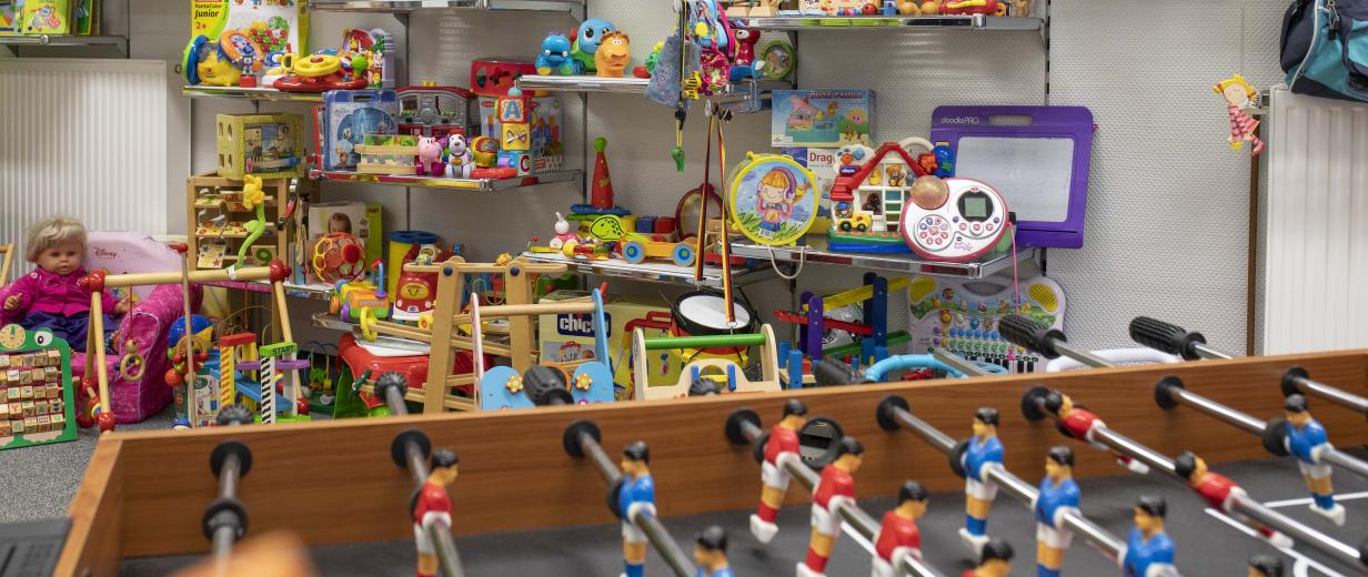 Eine Menge Spielzeug steht in einem Raum auf Wandregeln und davor.