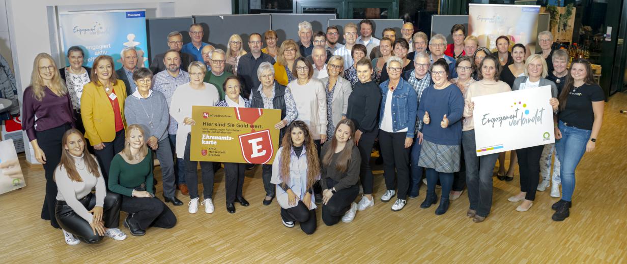 Ehrenamtskarte 2022 Eine große Personengruppe hat sich im Halbkreis aufgestellt und schaut in die Kamera.