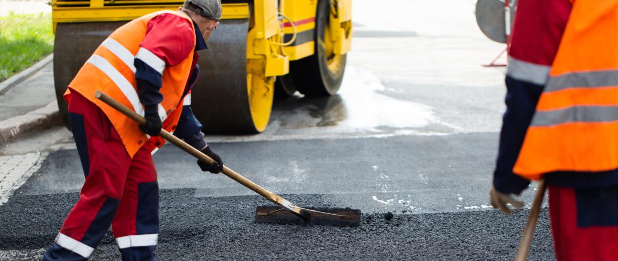 Geplante Baumaßnahmen an Kreisstraßen Straßenbauarbeiter verteilen Schotter