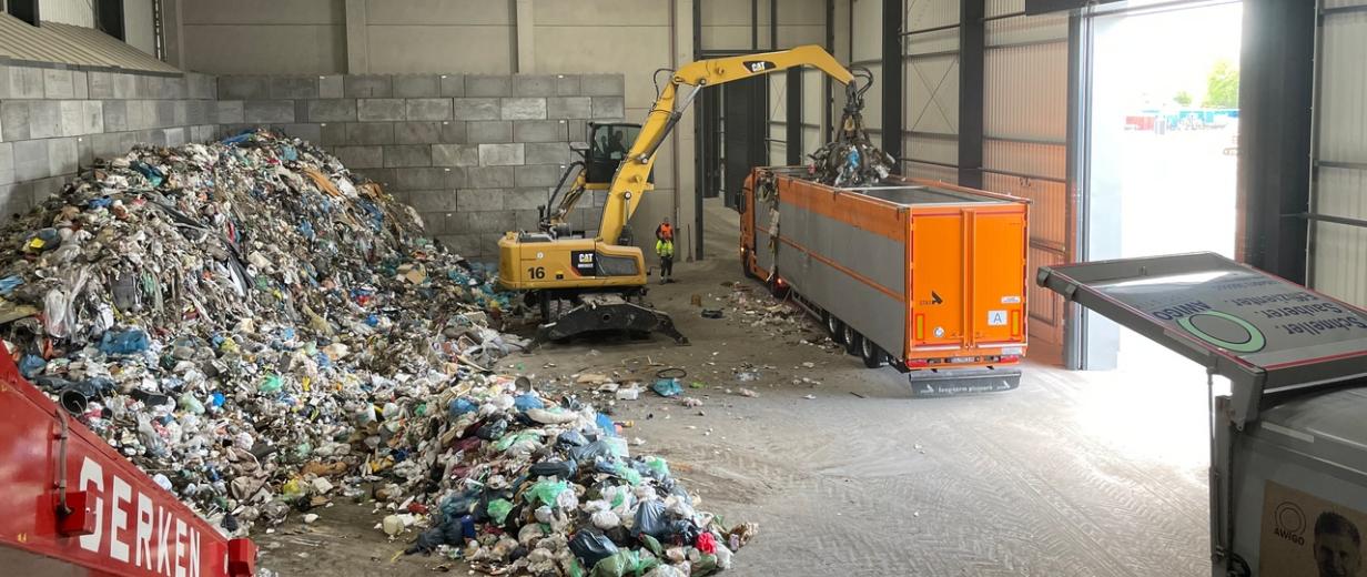 Innenansicht einer Lagerhalle mit Bagger und LKW