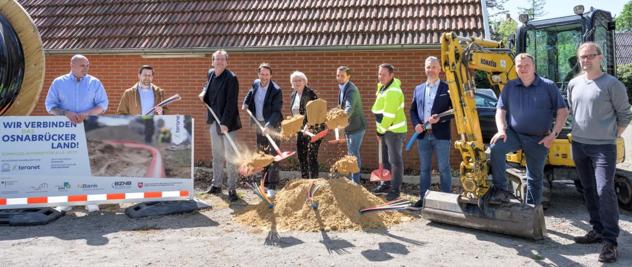 Eine Peronengruppe mit Schaufeln steht hinter einem Sandhaufen.