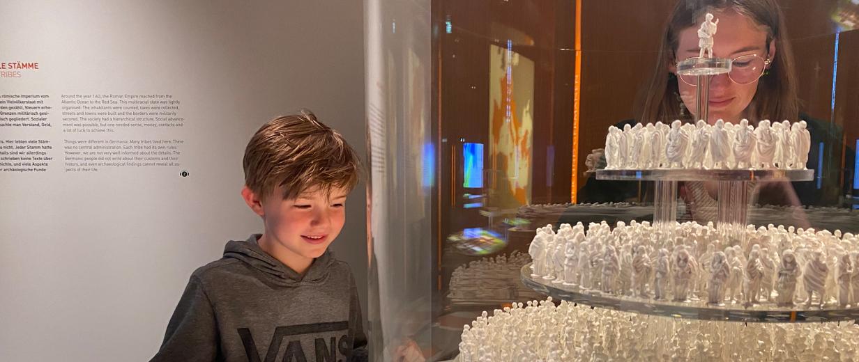 Sommerferienprogramm Varusschlachtmuseum Kalkriese Zwei Personen schauen in eine Vitrine in einer Ausstellung.