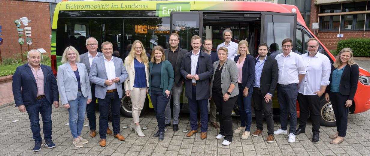 Eine Personengruppe steht vor einem Kleinbus.