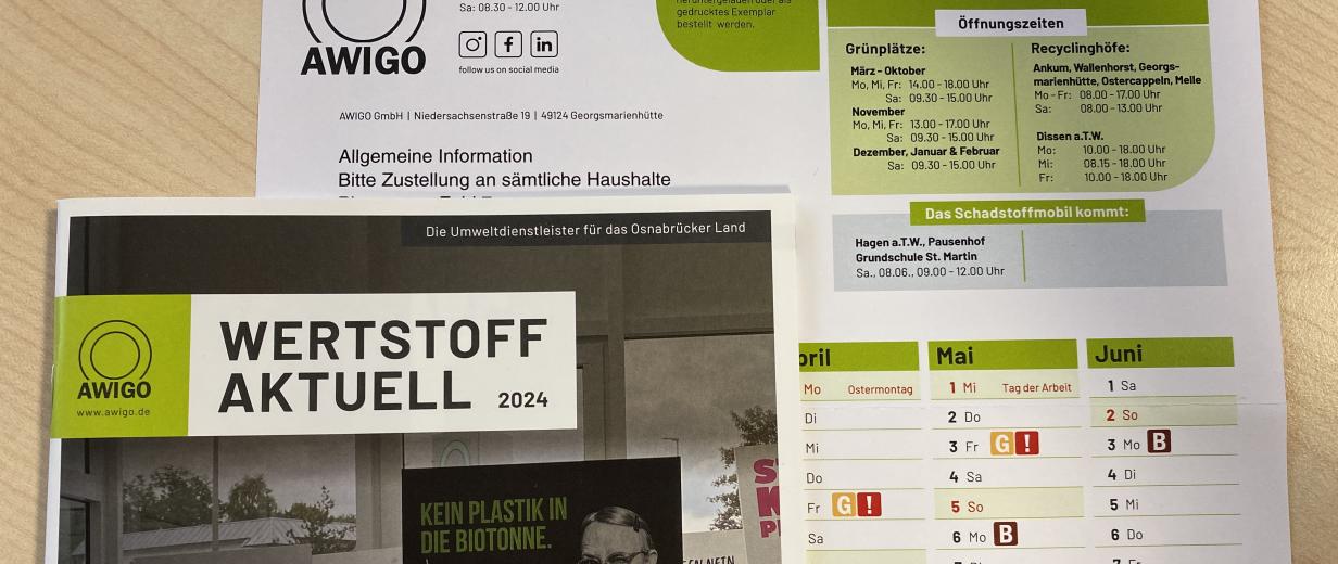 Kalender und Broschüren liegen auf einem Holztisch.