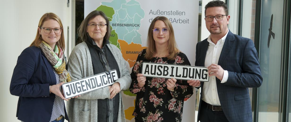Ausbildungscenter MaßArbeit Vier Personen stehen vor einem Roll Up Poster.