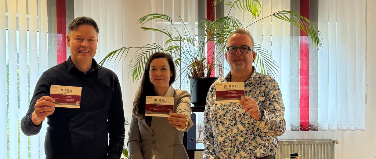 3 Personen vor Tisch stehend