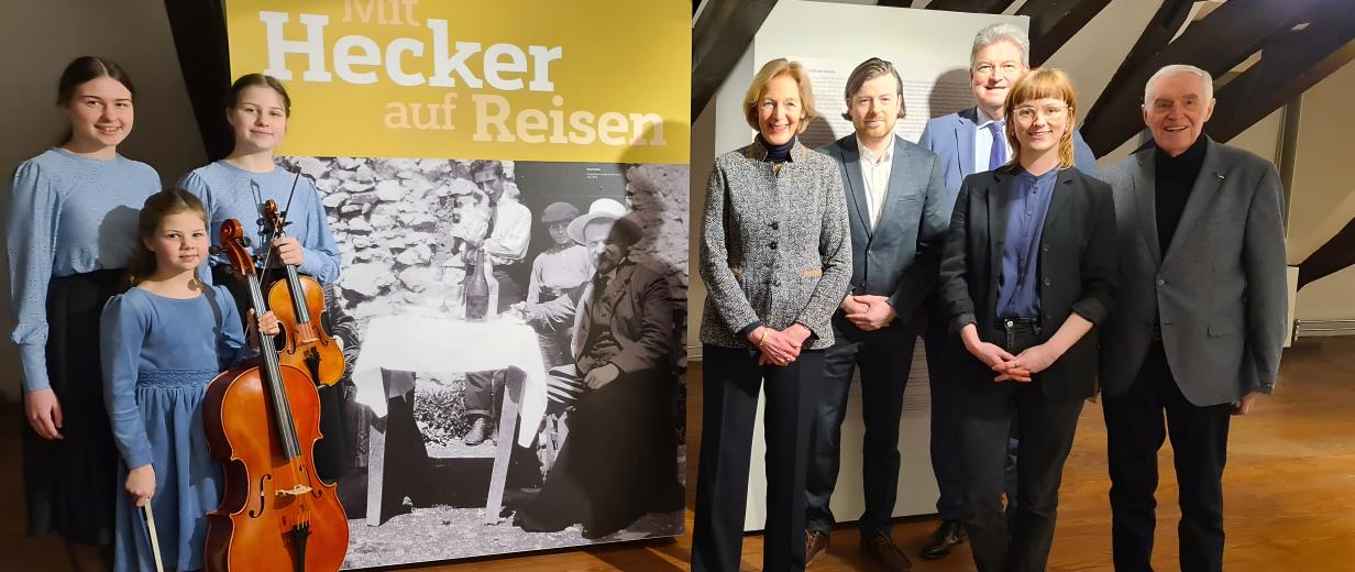 Eine Personengruppe steht vor Roll-Up-Postern.