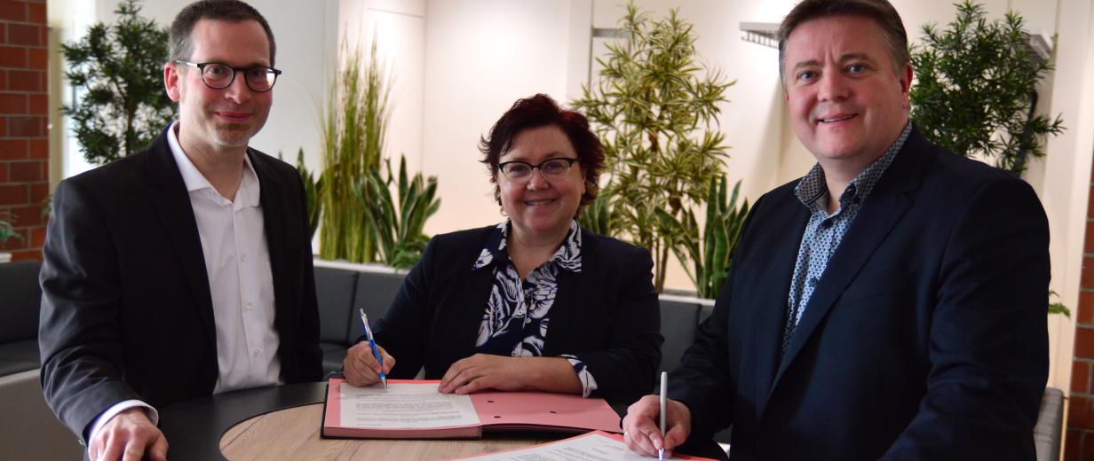 3 Personen vor Tisch stehend