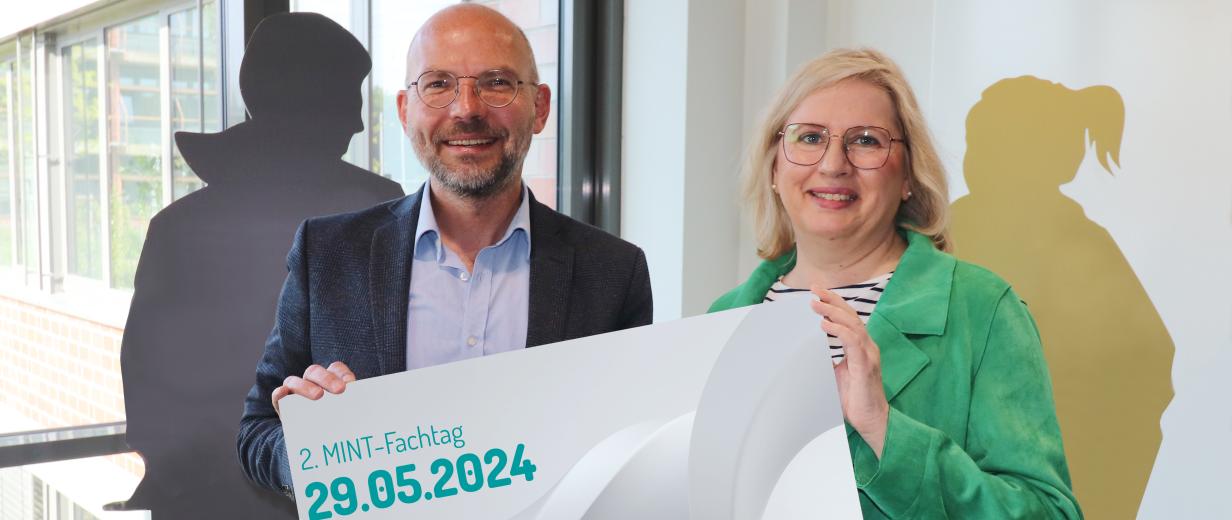 WIGOS lädt zum MINT-Fachtag am 29. Mai ins Kreishaus ein 2 Personen mit Plakat