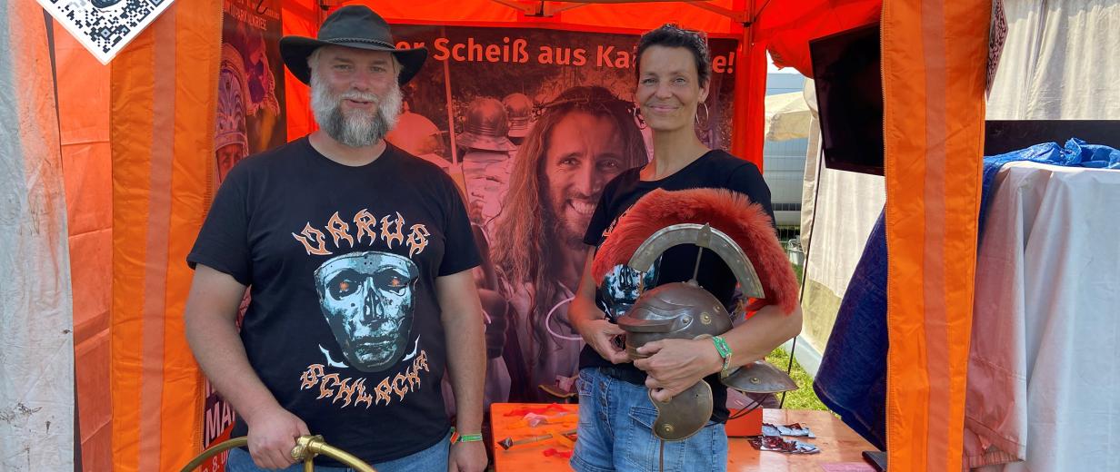 Kalkriese Varusschlacht Museum Wacken Zwei Personen stehen vor einem orangefarbenen Pavillon.