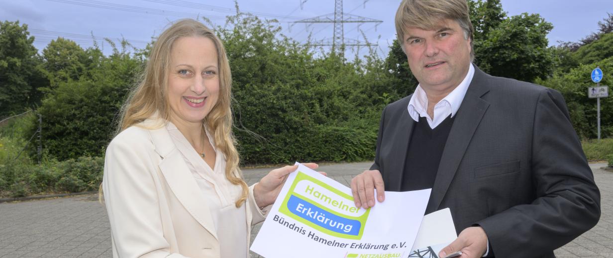 Hamelner Erklärung Zwei Personen stehen vor einer Hochspannungsleitung.