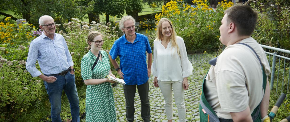 BIW Besuch Landrätin Fünf Personen stehen in einem Garten.
