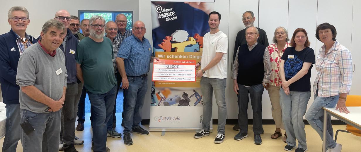 AWIGO, Repaircafe, Spende Eine Personengruppe steht links und rechts neben einem Rollup-Poster