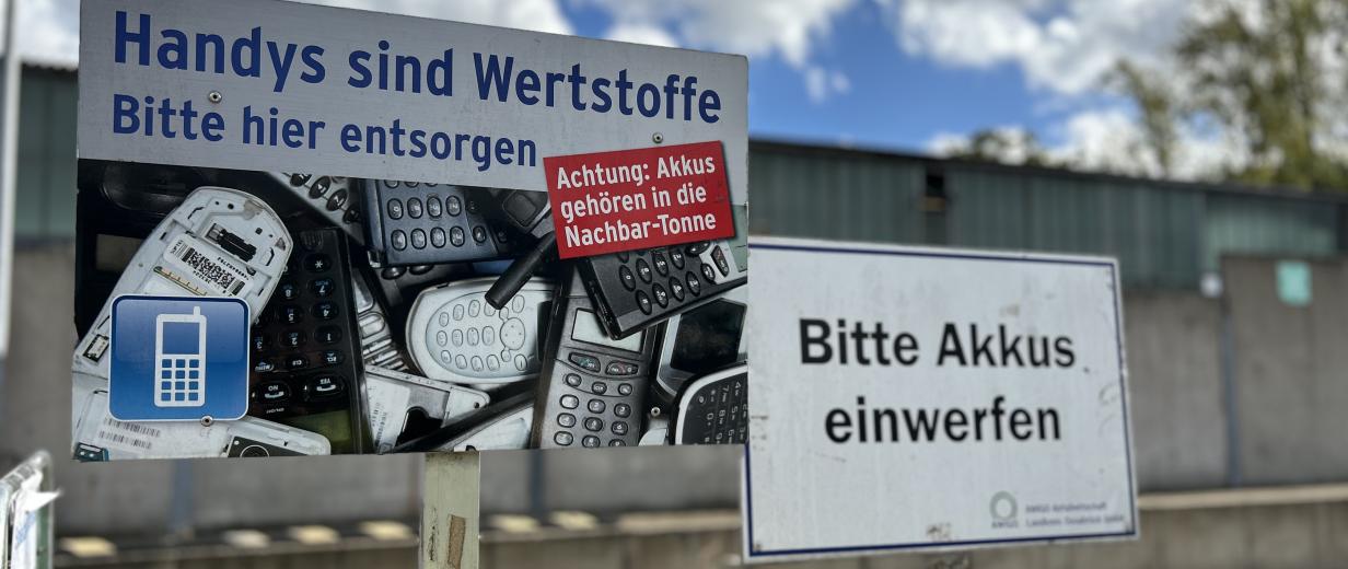 AWIGO, Akkus korrekt entsorgen Hinweisschild auf einem Wertstoffhof mit der Aufschrift "Handys sind Wertstoffe"