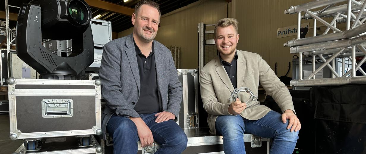 WIGOS, tomore music, Bersenbrück Zwei Personen sitzen auf Bühnentechnik-Elementen.