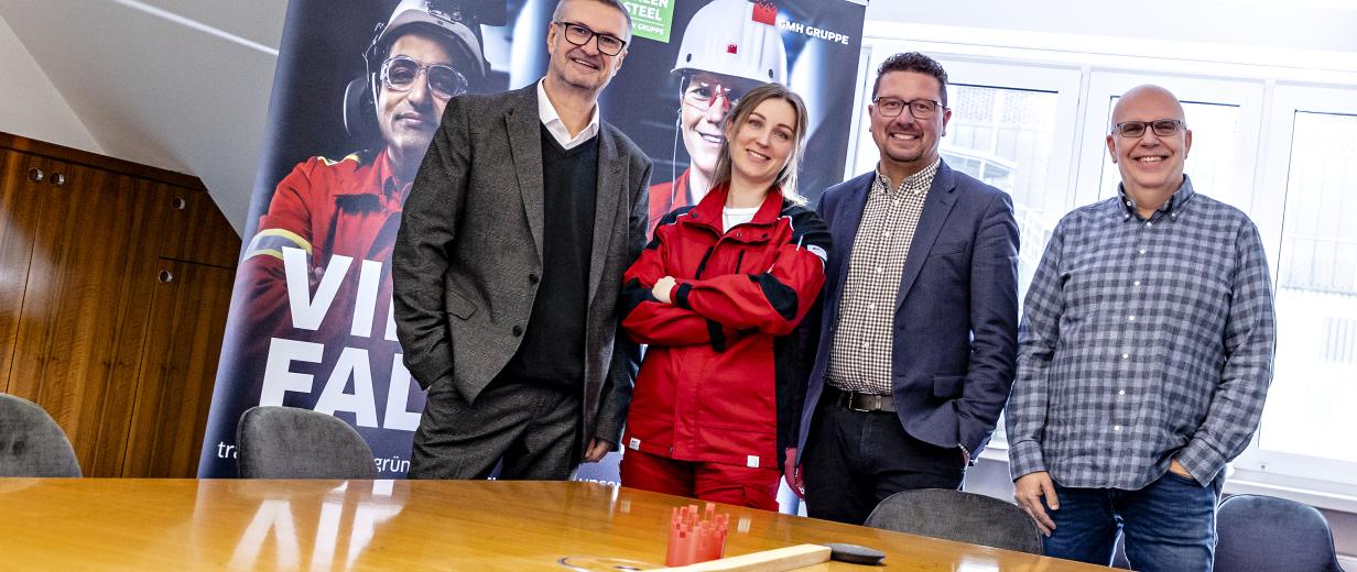 MaßArbeit vermittelte der Kranfahrerin den Arbeitsplatz „auf der Hütte“ 4 Personen vor einem Tisch stehend