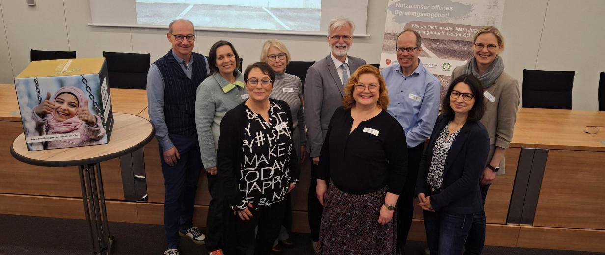 JBA Treffen, MaßArbeit Eine Personengruppe steht in einem Versammlungssaal.