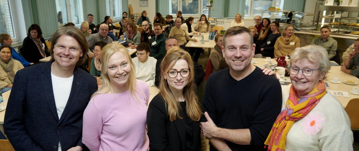 KI, Netzwerktreffen, MaßArbeit Fünf Personen stehen in einer Reihe, im Hintergrund ein Sitzungssaal.