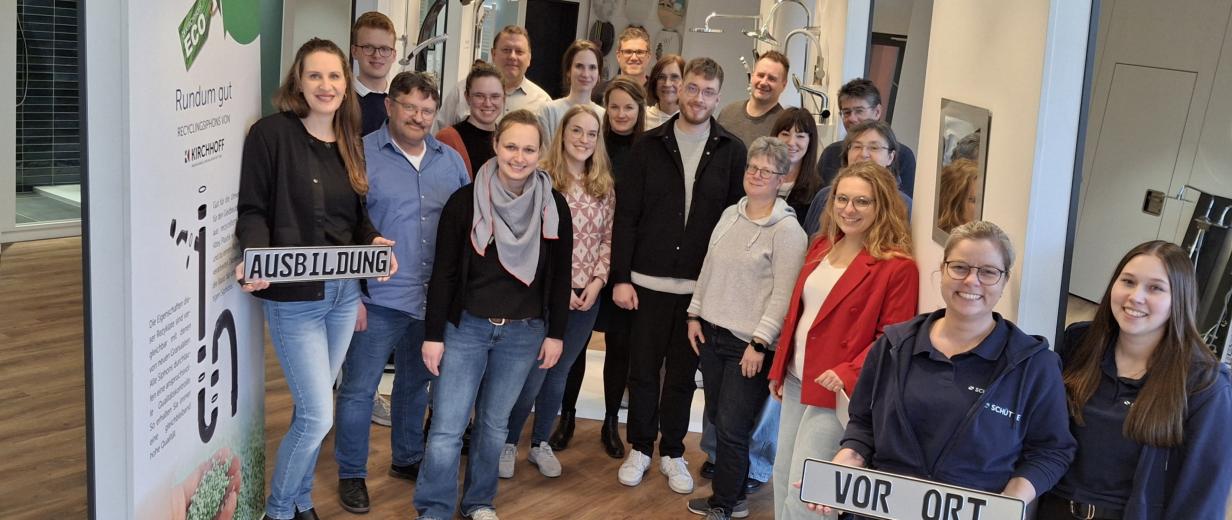 MaßArbeit, Schütte Eine Personengruppe steht im Ausstellungsraum eines Sanitärunternehmens.