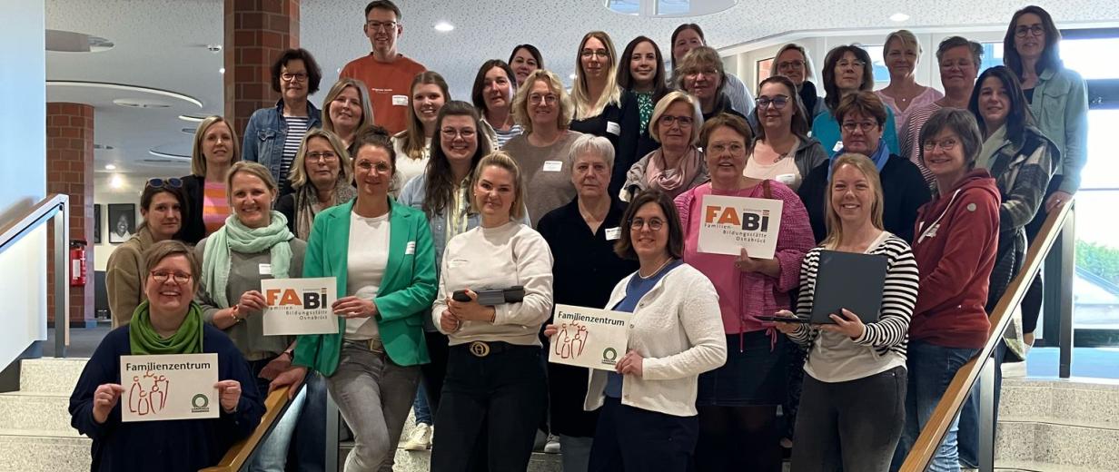 Kath. FABI, Familienzentren, Online-Elternabende Eine Personengruppe steht auf einer Treppe in einem Foyer.