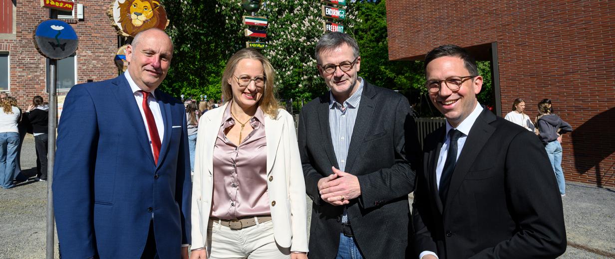 Aktion "Zeichen des Friedens" Vier Personen stehen vor einem Backsteingebäude.