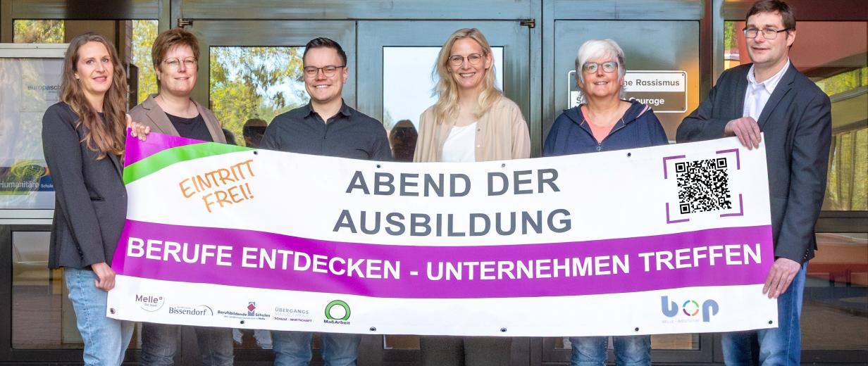 B.O.P. Melle-Bissendorf Sechs Personen mit einem Werbebanner in den Händen stehen vor einem Gebäudeeingang.