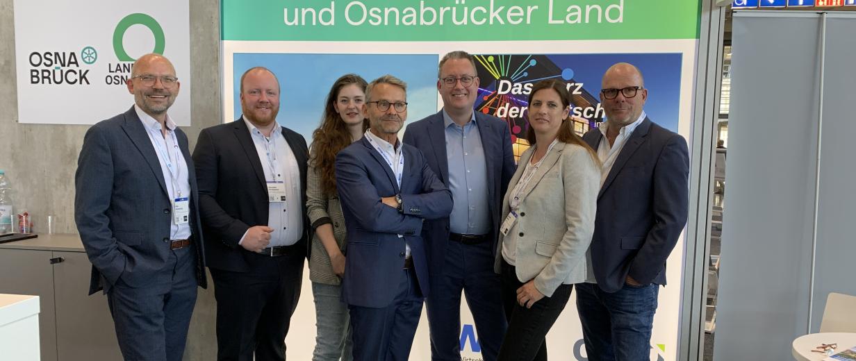 Eine Personengruppe steht auf einem Messestand.