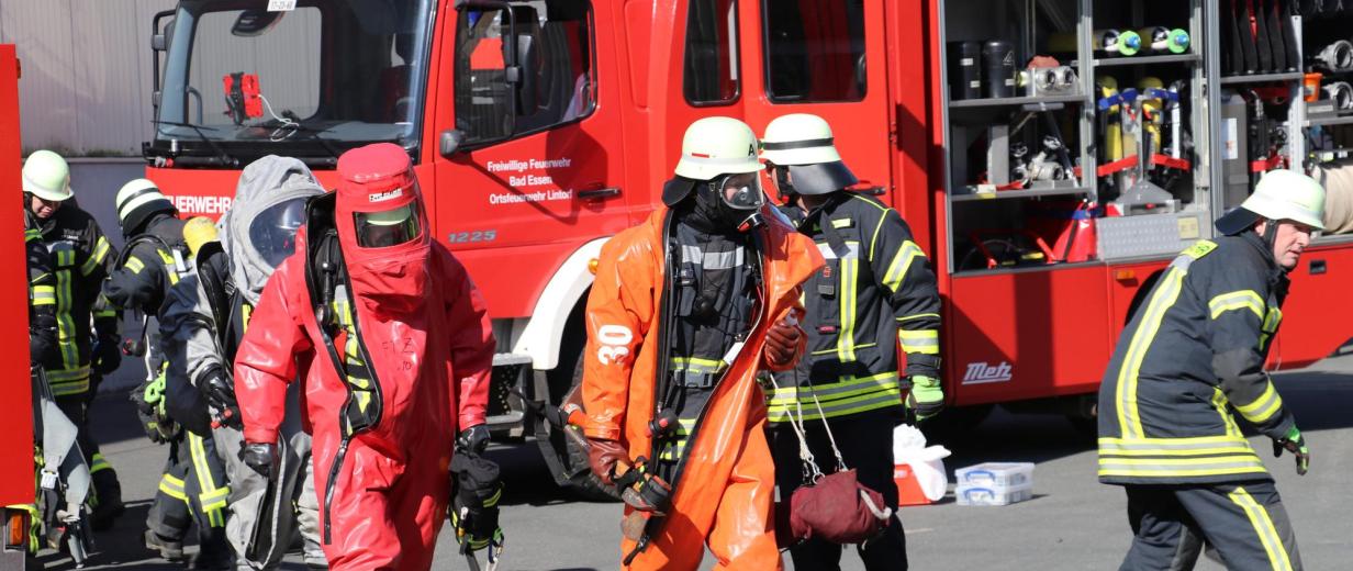 Personen in Schutzkleidung vor einem Feuerwehrfahrzeug