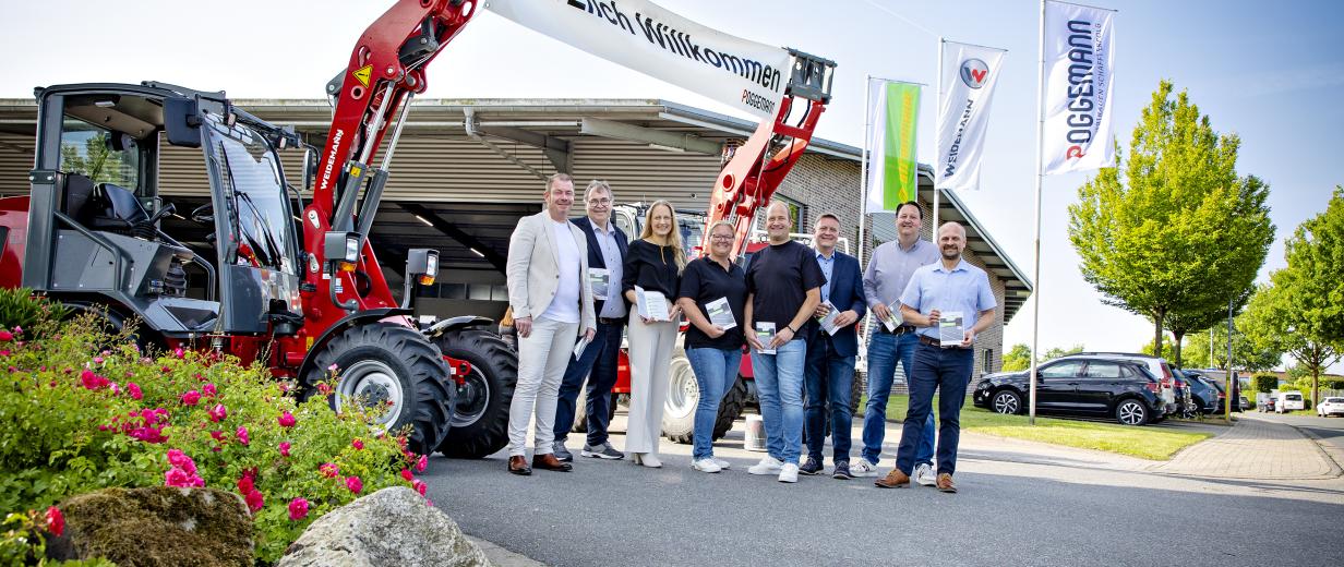 Acht- und Neuntklässler erkunden Berufe in den Hallen der Poggemann GmbH Gruppe von Personen vor Bagger