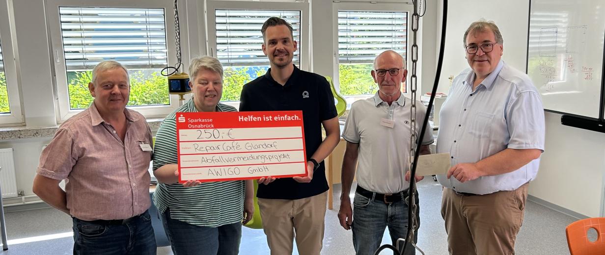 Fünf Personen präsentieren ein symbolischen Spendenscheck