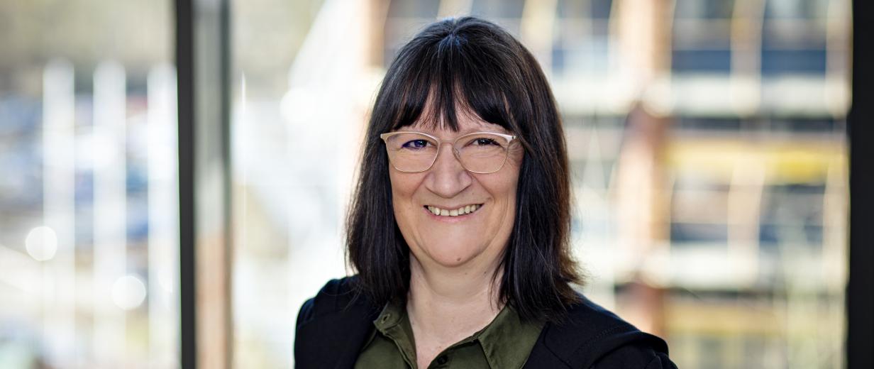Miriam Flint ArbeitgeberService MaßArbeit Eine Person steht vor einem Fenster.