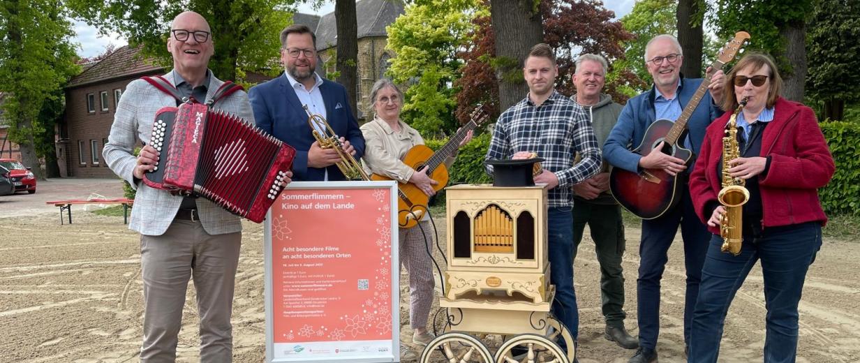 Sieben Personen mit Musikinstrumenten stehen auf einem Hof.