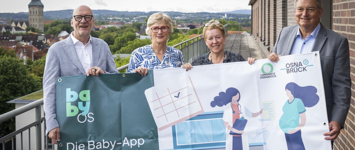 Baby-App für Stadt und Landkreis Osnabrück 4 Personen mit Plakat im Freien