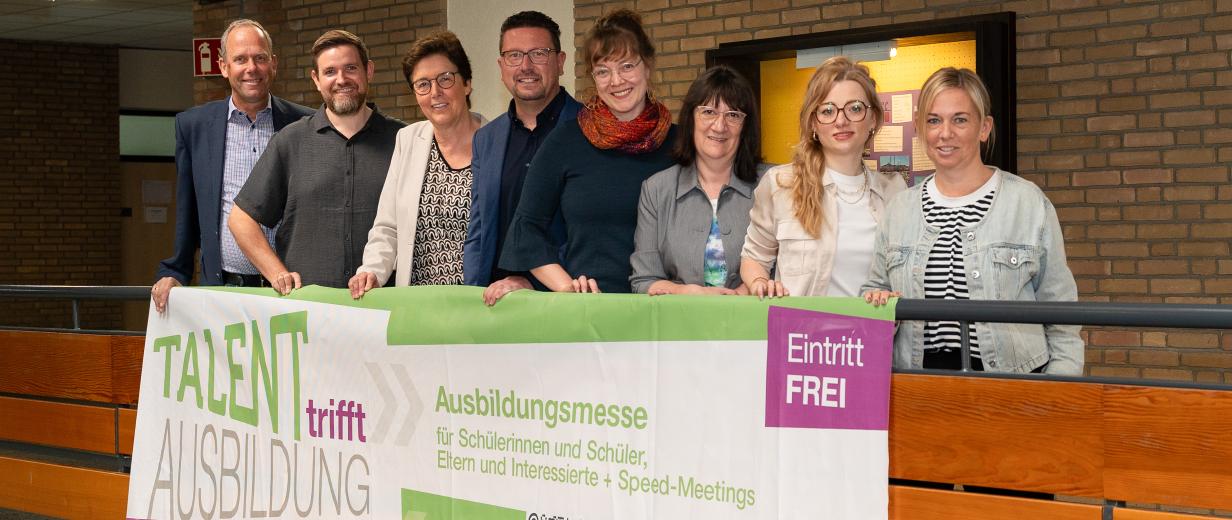Talent trifft Ausbildung Hagen a.T.W. Eine Personengruppe steht auf einer Empore, an der ein Plakat befestigt ist.