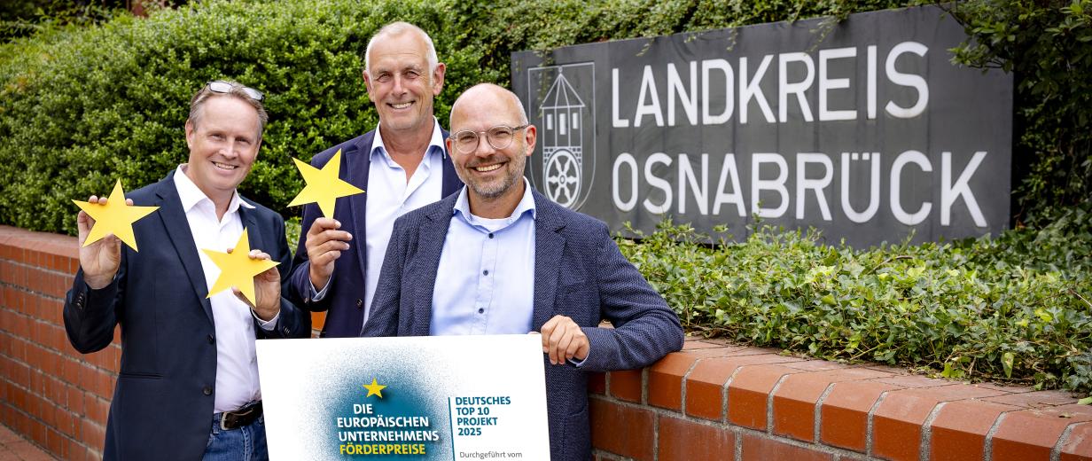 WIGOS Auszeichnung Unternehmensförderung Drei Person stehen vor einem Gebäude.