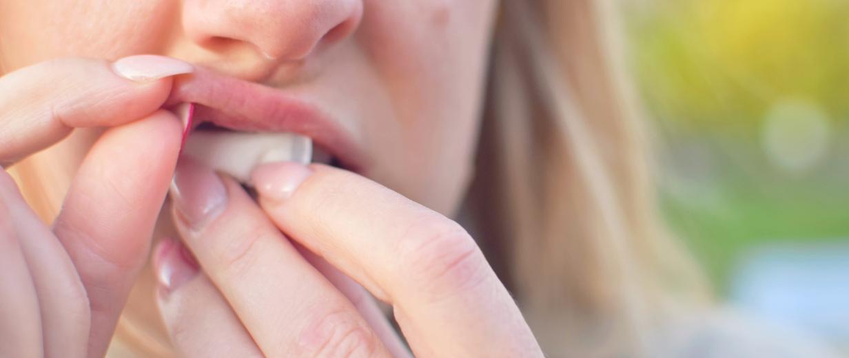 Frau schiebt sich Nicotine Pouches unter die Lippe