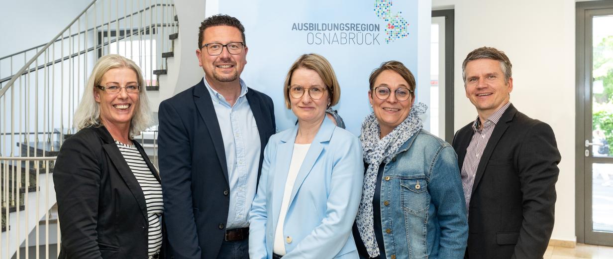 Ausbildungsregion Verein Internetportal Fünf Personen stehen vor einem Rollup-Poster in einem Treppenhaus.