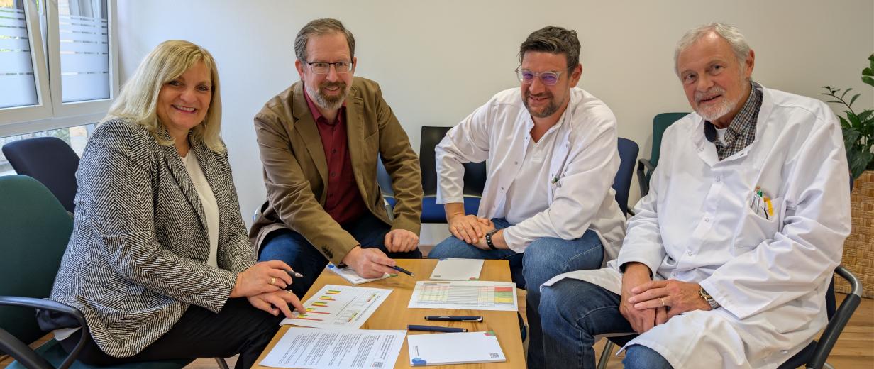Hausärzteversorgung Förderung GMhütte Vier Personen sitzen in einem Raum.